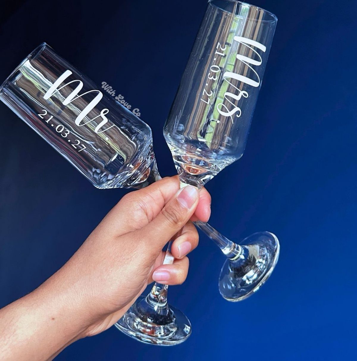 Two engraved champagne flutes with Mr and Mrs and a date held together.