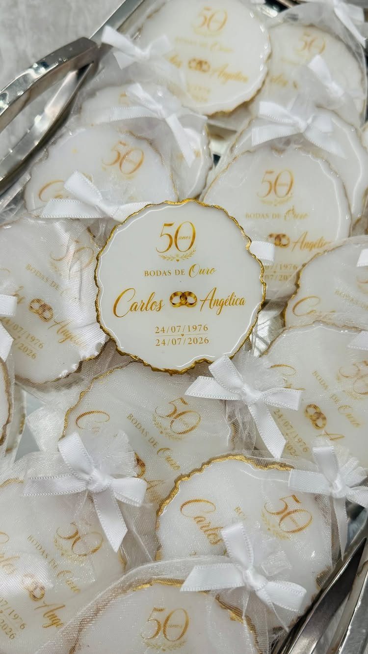White and gold 50th anniversary cookies wrapped in tulle on a silver tray