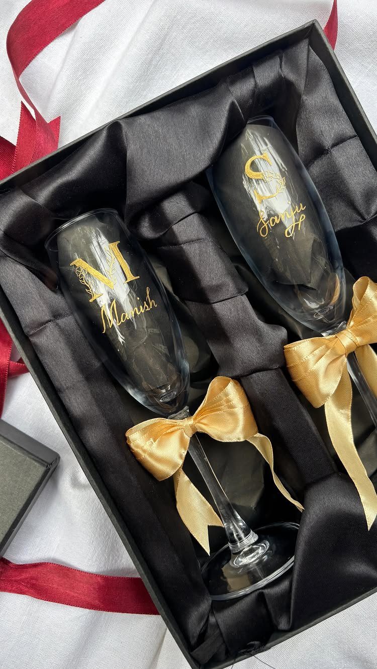 Engraved champagne flutes with gold lettering and bows in a black gift box