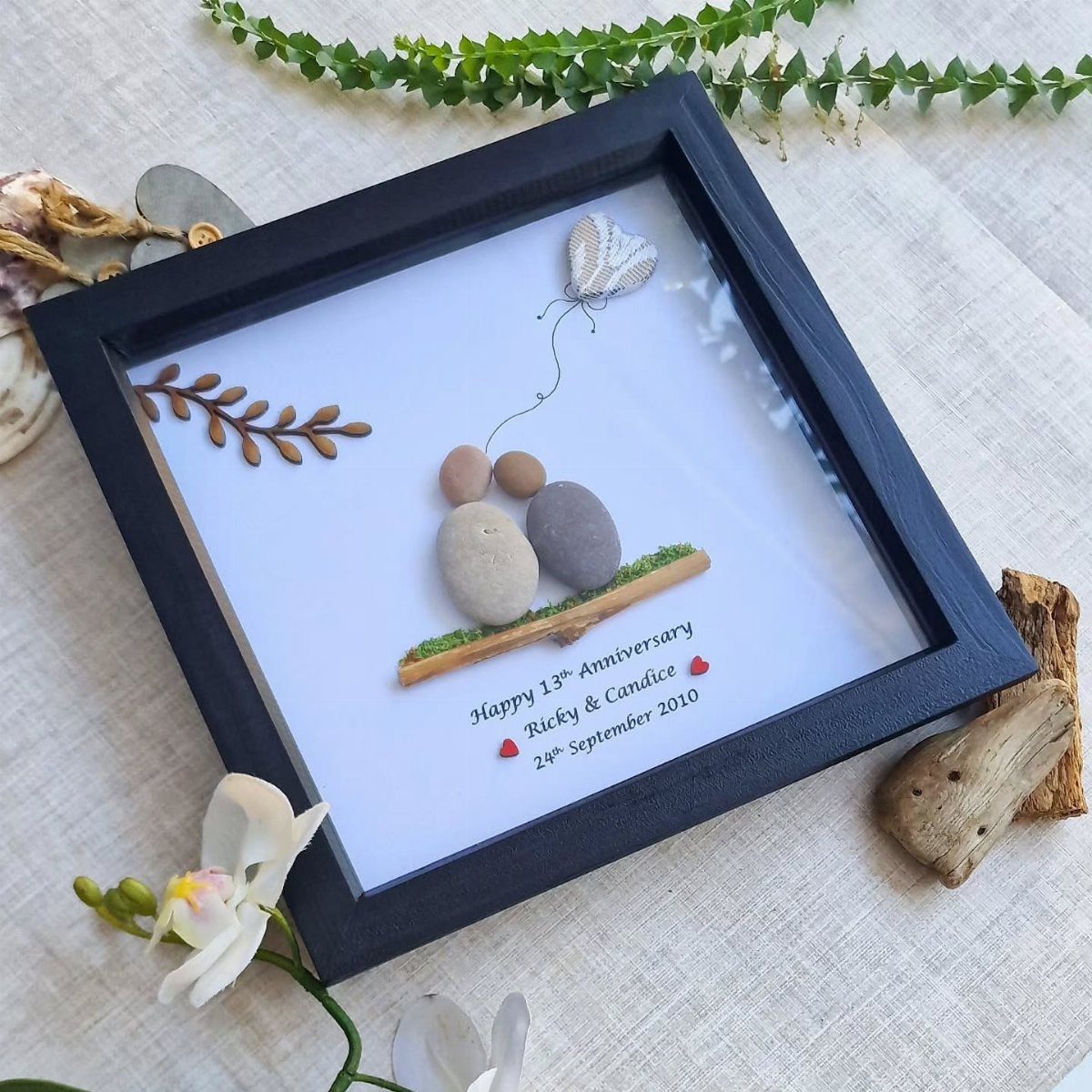 Pebble art anniversary gift in a black frame with personalized anniversary text.