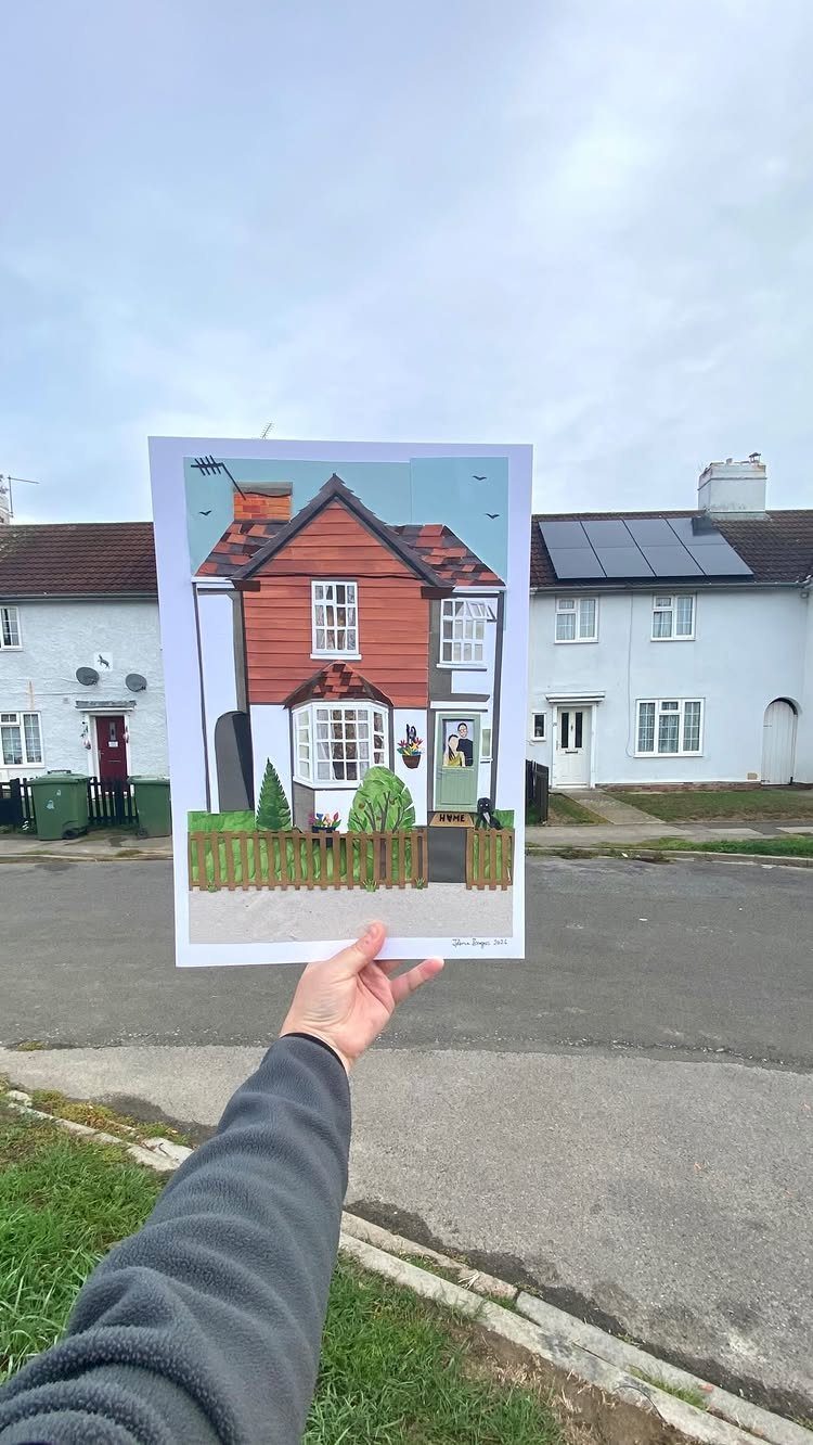 Illustrated house portrait print held up in front of the real white house.
