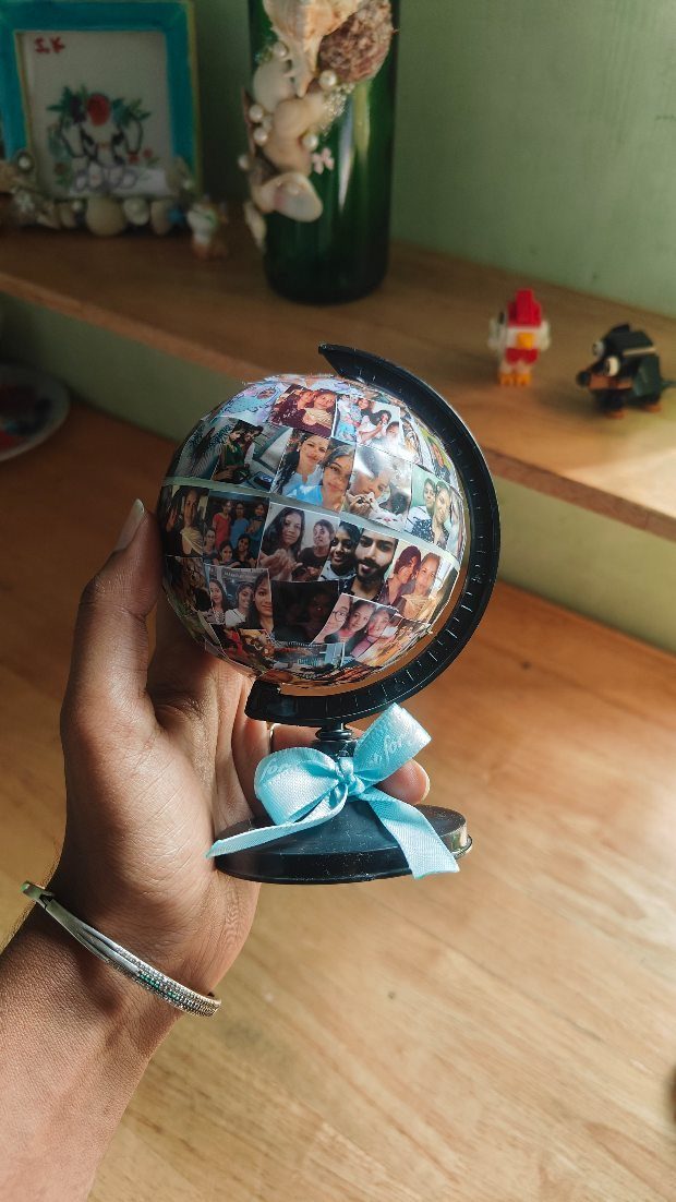 Small decorative globe covered in personal photo collage with a blue ribbon bow.