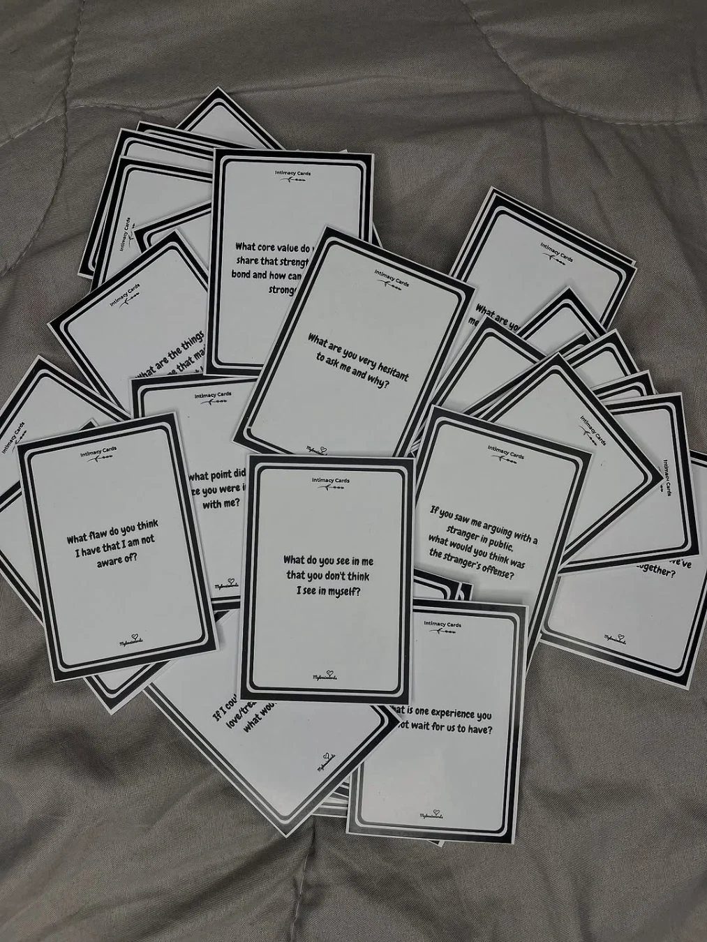 Scattered white prompt cards with black borders and text on grey fabric.