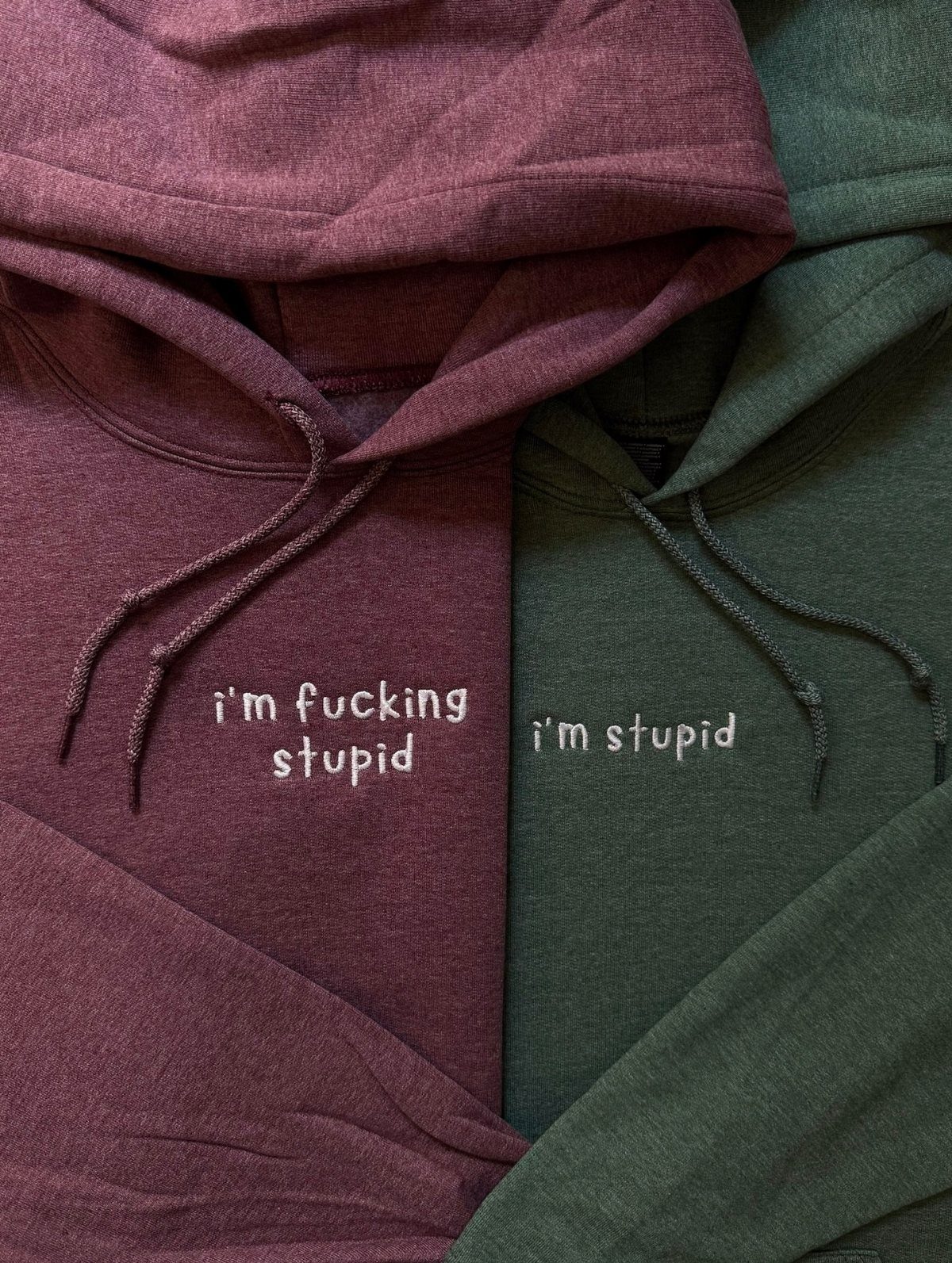 Maroon and green hoodies with embroidered phrases about being stupid on the chest.