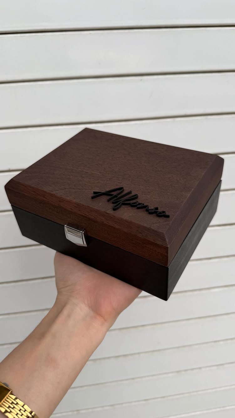 Wooden gift box with engraved name held by a person against white wall