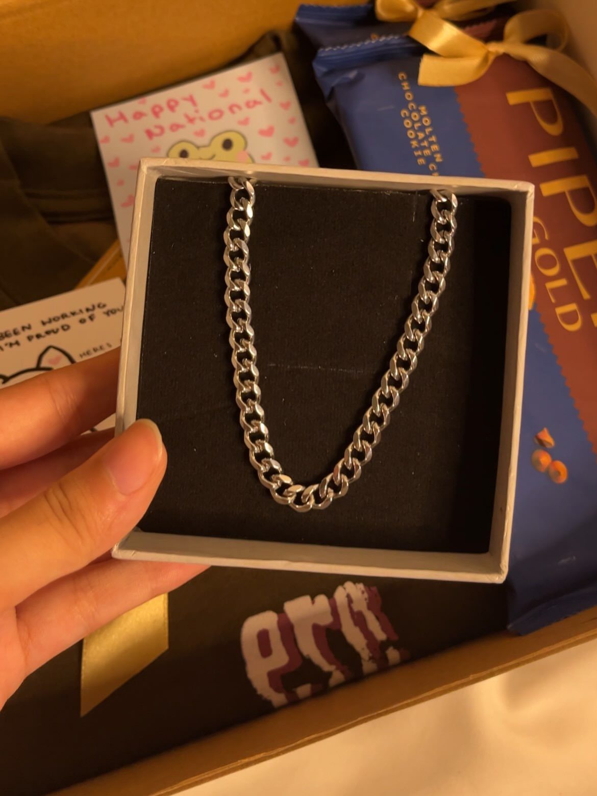 Silver curb chain necklace in a jewelry box with chocolates and a note.