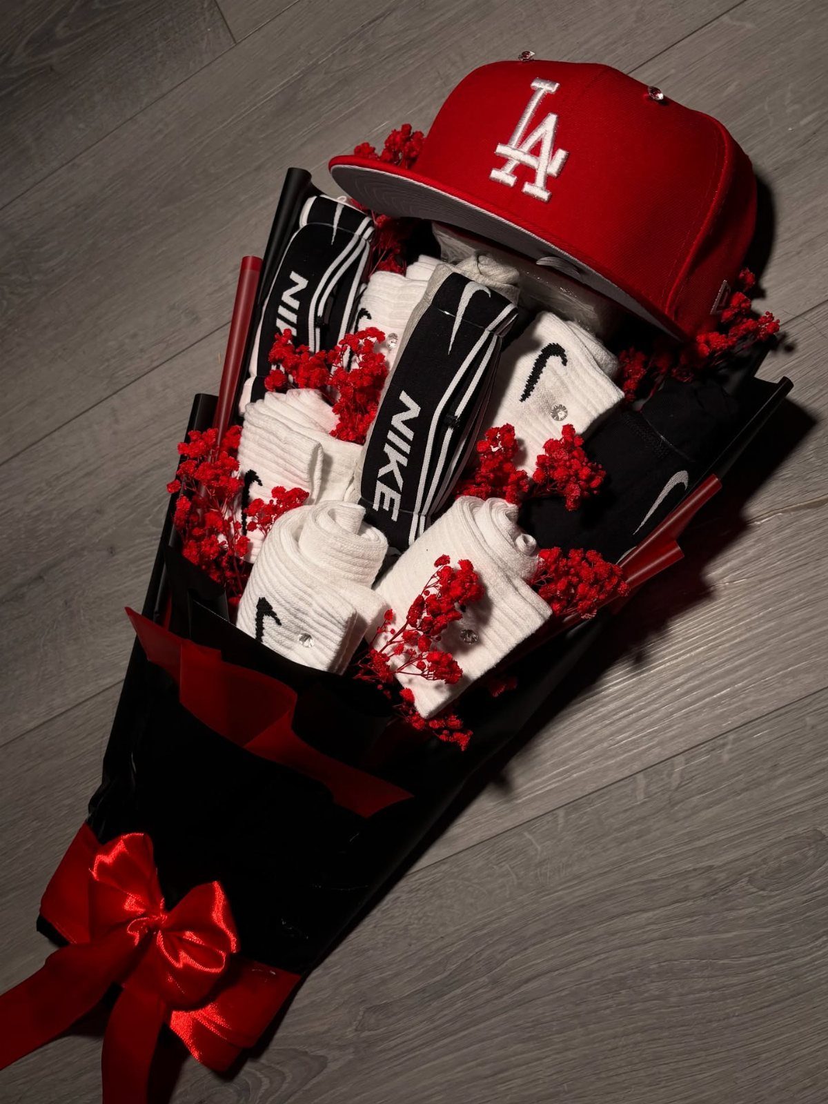 Gift bouquet with Nike socks and a red LA Dodgers cap wrapped in black.