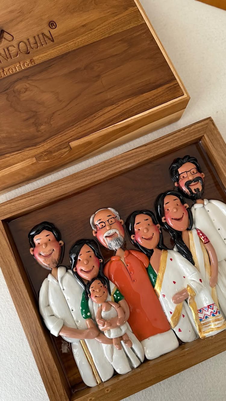 Custom clay family figurines in a wooden box showing three generations of people.