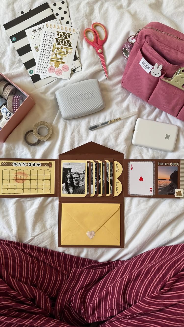 Handmade brown scrapbook with photos and a yellow envelope on white bedding
