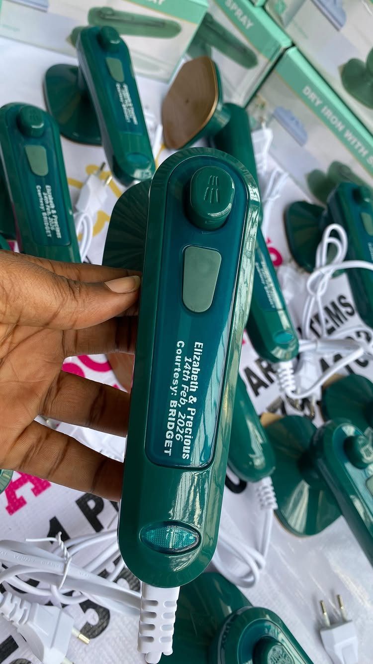 Small green travel iron held by a hand among several other irons.